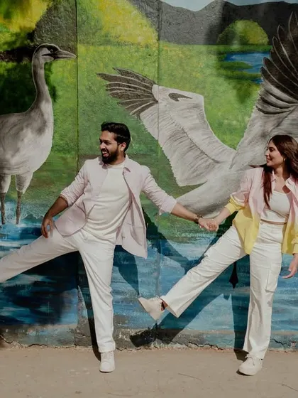 A quirky and fun pose with the couple mimicking the birds in the mural behind them.