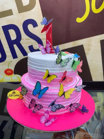 A 2kg two-tiered first birthday cake with a pink ombre design and a flutter of colorful butterflies.
