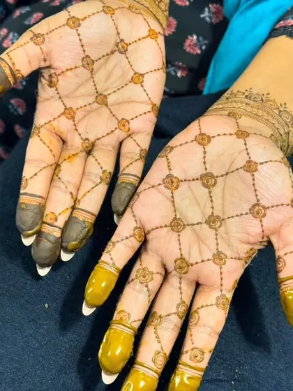 A very delicate and simple 'jaal' design with tiny flowers at each intersection. The henna-dipped fingertips add a touch of tradition.