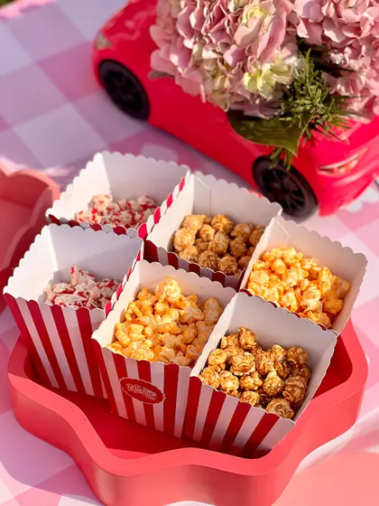 A variety of flavored popcorn served in classic striped boxes, perfectly matching the party's fun, whimsical vibe.