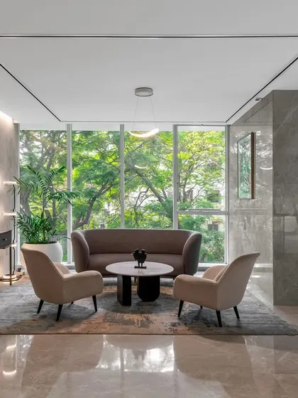 A quiet seating area in the Asian Paints office, with large windows overlooking a lush green landscape. The use of muted tones, natural materials, and comfortable furniture creates a serene space for relaxation and focused conversation.