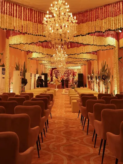 A long view of the hall decorated for a traditional ceremony. The ceiling is completely covered in garlands of fresh flowers, and magnificent crystal chandeliers add a touch of grandeur to the sacred space.