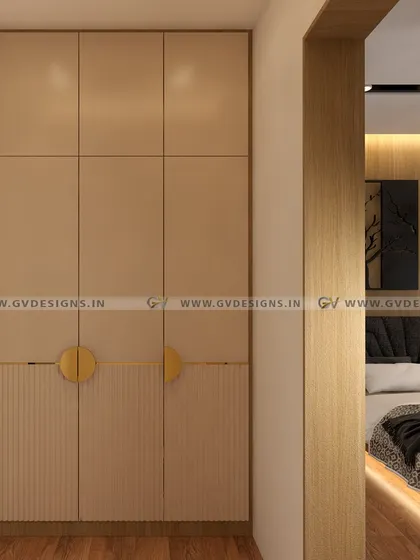 This floor-to-ceiling wardrobe design combines wooden and beige laminate for a warm, sophisticated look. The bottom half features fluted lamination for texture, while the paired semicircle handles add a unique and functional design element.