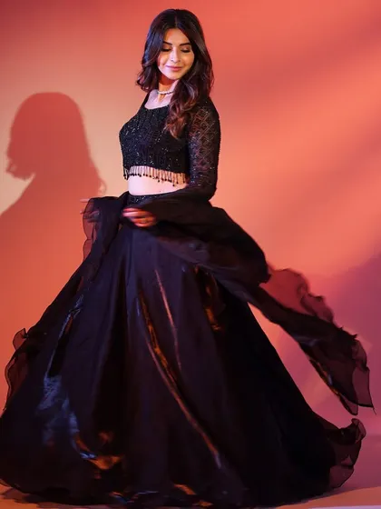 A twirling shot of the black lehenga, showing the beautiful movement of the skirt. The subtle sparkle and dramatic sleeves make it a timeless choice.