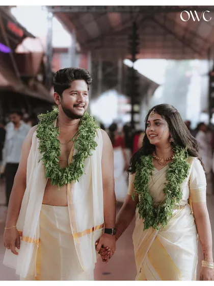 A happy couple walks hand-in-hand through a crowded temple, their smiles lighting up the frame.