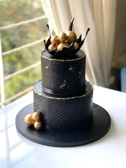 A bold and elegant 50th birthday cake, featuring a complete black ganache finish. The bottom tier is detailed with ganache stenciling, showing how versatile this medium can be.