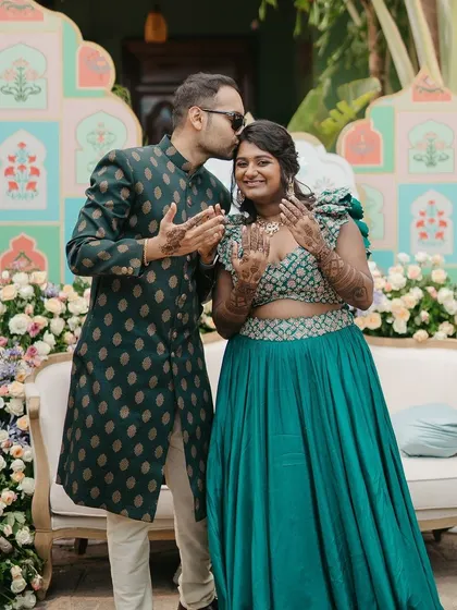 A sweet moment as the groom gives his bride a kiss on the forehead during their Mehendi photoshoot.
