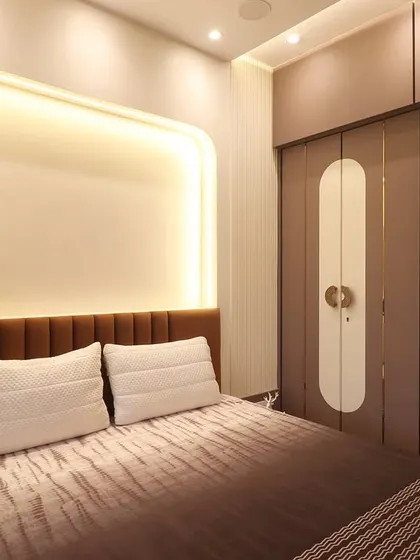 A view of the same bedroom, showcasing the custom wardrobe design. The wardrobe doors feature elongated, rounded white panels with unique handles, adding a graphic and stylish element to the room.