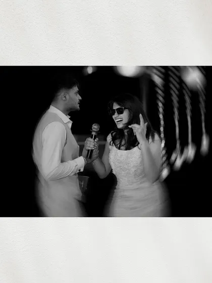A candid black and white shot of the couple singing karaoke, their joyful and carefree expressions perfectly captured.