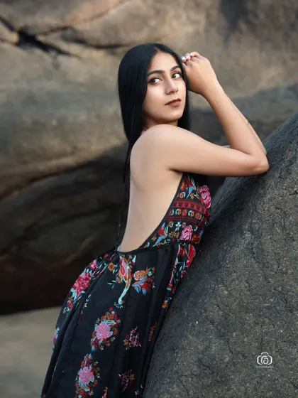 A close-up portrait of the model in the floral dress. The focus is on her expression and the beautiful, soft lighting of the beach environment.