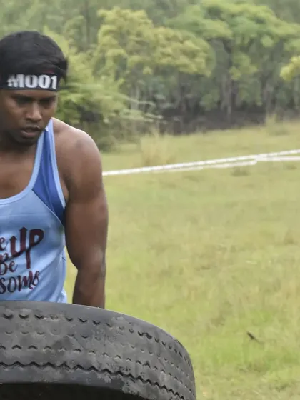 Flipping a heavy tractor tyre during an obstacle course race. This movement requires total-body strength, from your legs and back to your chest and arms, and is a staple in my power training programs.