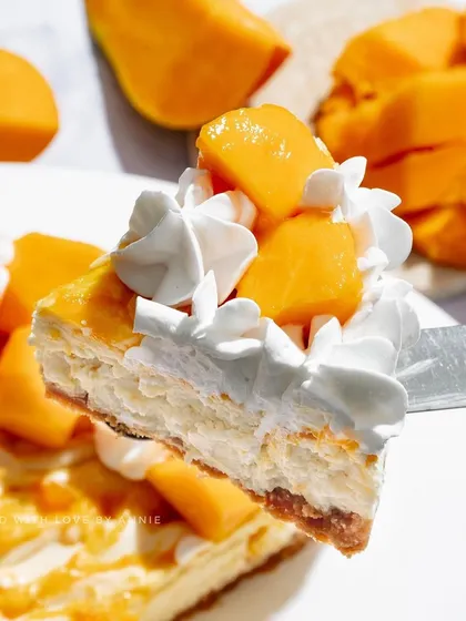 A perfect slice of my Baked Mango Cheesecake, topped with whipped cream and fresh mango chunks.