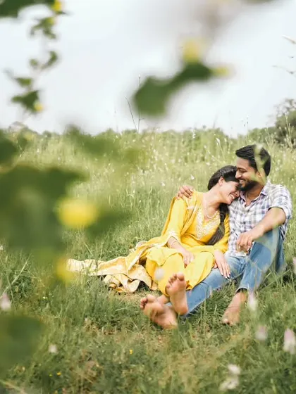 A candid moment of rest and affection during a pre-wedding shoot in a beautiful meadow.