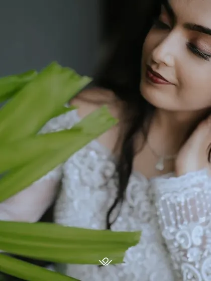 A close-up portrait of a Christian bride, framed by lush green leaves, creating a natural and intimate feel.