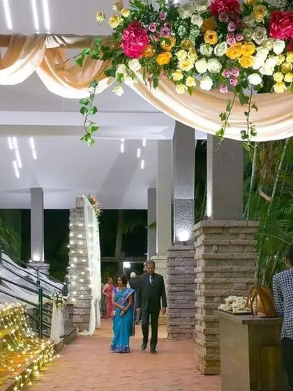 A lush and beautiful floral archway for a wedding entrance. The combination of colorful flowers, green foliage, and soft lighting creates a stunning welcome for your guests.