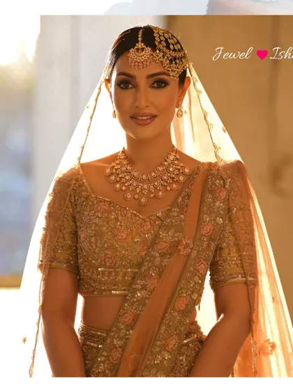 A full-length portrait of the bride against a sunlit window, creating a beautiful, ethereal glow. Her entire look, from the pastel lehenga to the polki set, is pure perfection.