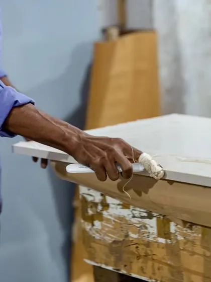 While we use advanced machinery, the final touch often requires a skilled hand. Here, a worker is applying adhesive for edge finishing, a testament to the detailed craftsmanship that goes into every piece.
