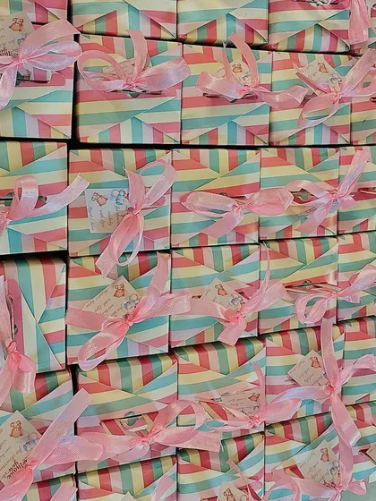A large batch of our pastel striped baby shower favor boxes, each tied with a pink ribbon and a custom tag.
