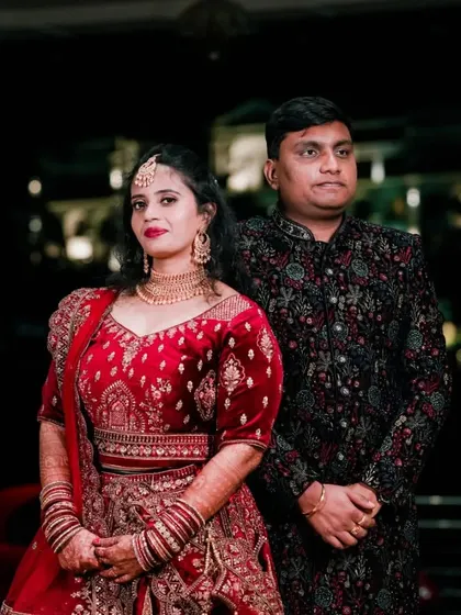 A classic full-length portrait of the couple at their reception. Their coordinated red and black outfits look stunning against the nighttime backdrop of the venue.