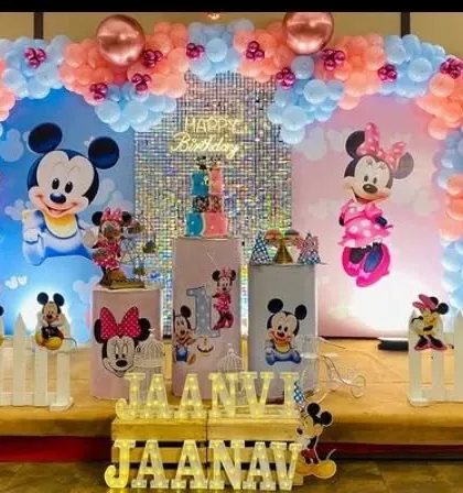 A classic Mickey and Minnie Mouse theme for a first birthday. The pink and blue color scheme is perfect for a joint celebration, with character cutouts and a sequin backdrop.