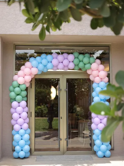 This mermaid-themed entrance uses a beautiful pastel balloon arch in shades of pink, blue, purple, and green, creating a magical underwater feel right at the door.