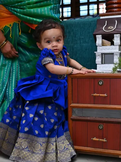 The standing pose shows how the Pattu Pavadai is constructed for a perfect fit. The top is tailored to sit comfortably, while the skirt allows for easy movement, making it a practical choice for active toddlers at family functions.