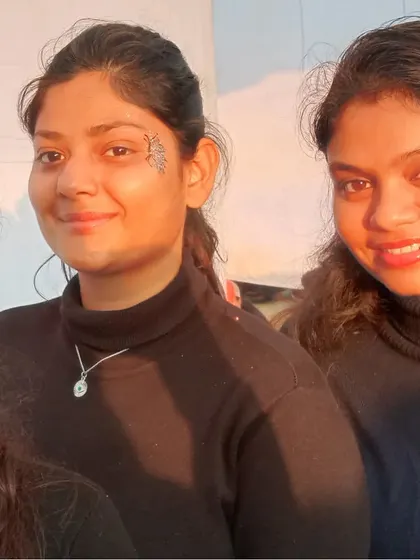Friends showing off their new face art in the golden hour light. One has a subtle floral design and the other a classic butterfly.