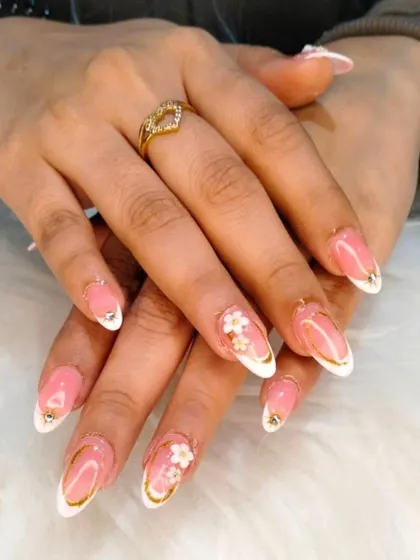 A beautiful set of almond-shaped nails combining a white French tip with delicate 3D floral embellishments and gold accents.