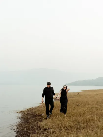 A minimalist shot of a couple walking by a serene lake. The misty, atmospheric quality of the light and landscape gives this photo a quiet and contemplative feel.