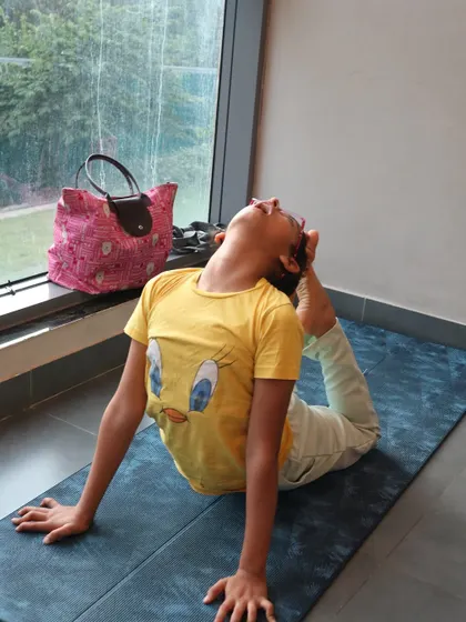 This young yogini practices a gentle backbend, opening her heart and building flexibility in her spine. Every practice, no matter how simple, is a step forward.