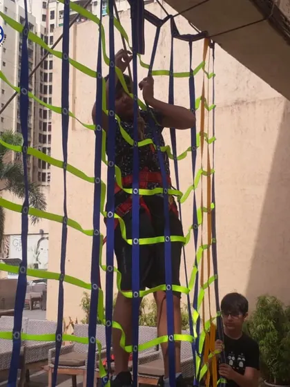 A young athlete tackles a climbing net, a challenging activity that builds upper body strength, grip, and determination.