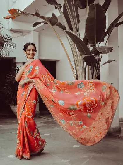 The model shows off the graceful drape of a peach-colored floral saree. The movement in the pallu adds a dynamic element to the photo, while the soft colors are perfect for a subtle, elegant look.