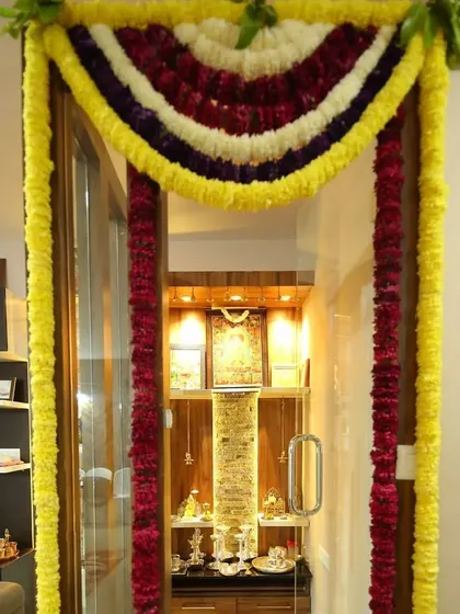 A floral decoration for a pooja room door during a housewarming. The mix of yellow, red, and purple flowers adds a divine touch to the sacred space.
