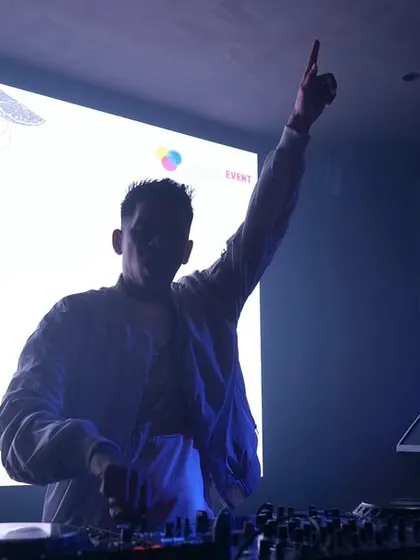 A silhouette shot against the bright VJ screen, raising a hand to the sky.