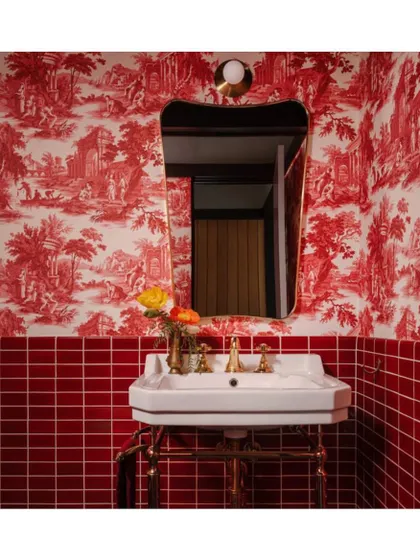 This powder room showcases how a bold, classic Toile de Jouy wallpaper in a striking red can be paired with modern red tiles for a showstopping effect. It's a perfect example of mixing classic patterns with contemporary elements.