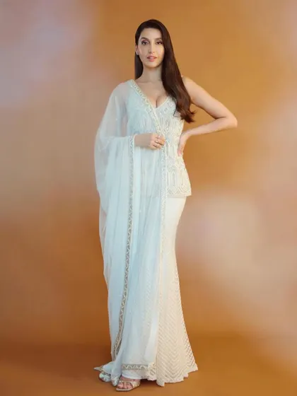 Nora Fatehi looks ethereal in this white peplum and sharara set by Ritika Mirchandani. This is a great example of fusion wear, blending traditional embroidery with a modern silhouette for a chic, celebratory look.
