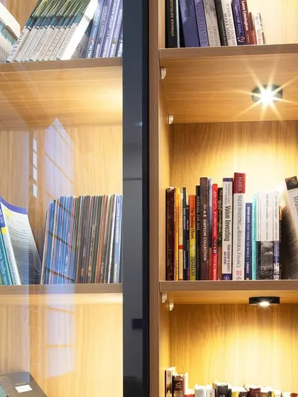 A close-up of a custom bookshelf, showing how warm wood tones and integrated spot lighting can turn a simple storage unit into a personal retreat for book lovers.