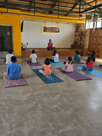 A wide shot of a kids' yoga session in progress during the summer camp. The spacious studio provides a perfect environment for them to learn and practice together.