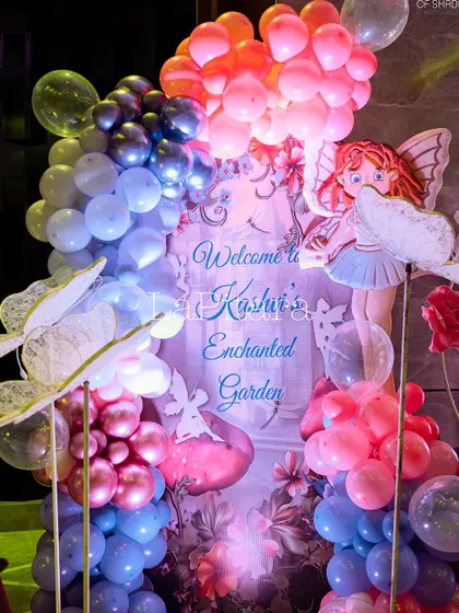 A welcome sign for 'Kashvi's Enchanted Garden', framed by a whimsical balloon arch and fairy cutouts.