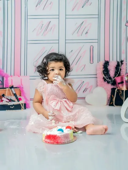 A little bit of frosting on her face makes for a perfect cake smash photo. This image shows the fun contrast between her pretty dress and the messy celebration.