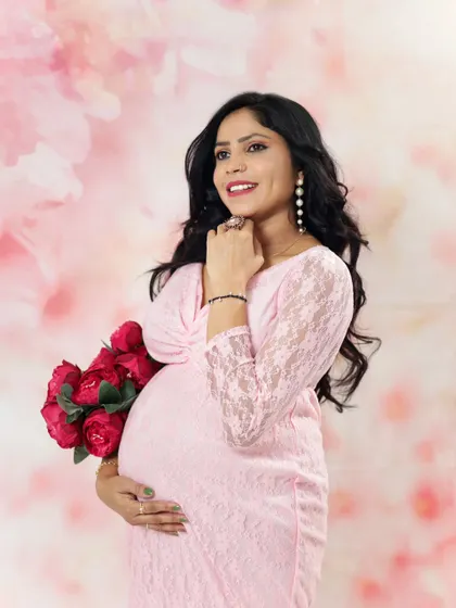 A glowing portrait of an expecting mother in a pink lace gown. Her happy expression and the soft lighting create a joyful and beautiful memory.