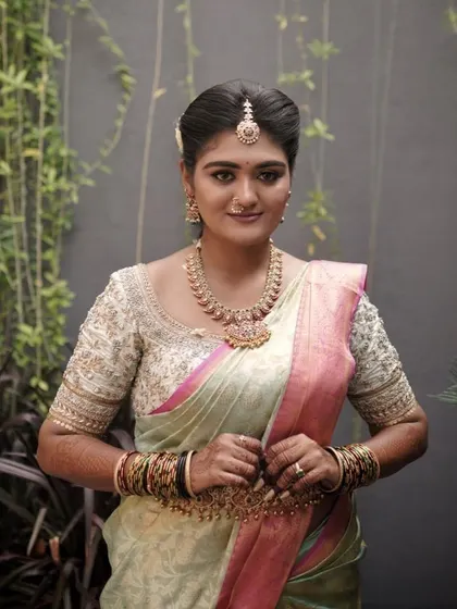 Another beautiful portrait of Ashitha, showcasing her complete look. The makeup ties together the pastel saree, embroidered blouse, and traditional jewellery.