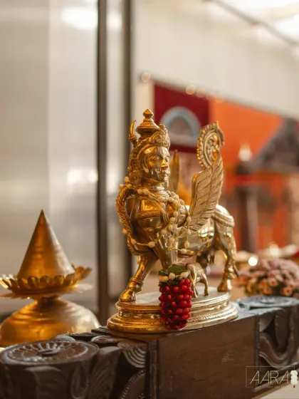 A gleaming brass statue of Garuda, a divine figure from Hindu mythology, adorned with a simple floral garland. Incorporating such powerful symbols is how I infuse a space with a sense of sacred history and storytelling.