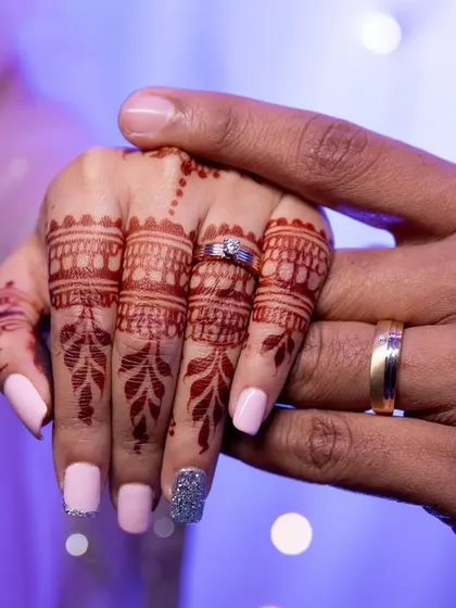A close-up of the couple's hands, showing their wedding rings.