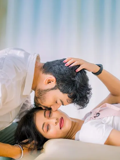 A tender forehead kiss, capturing a quiet, intimate moment. The couple's casual outfits make this shot feel very natural and authentic.