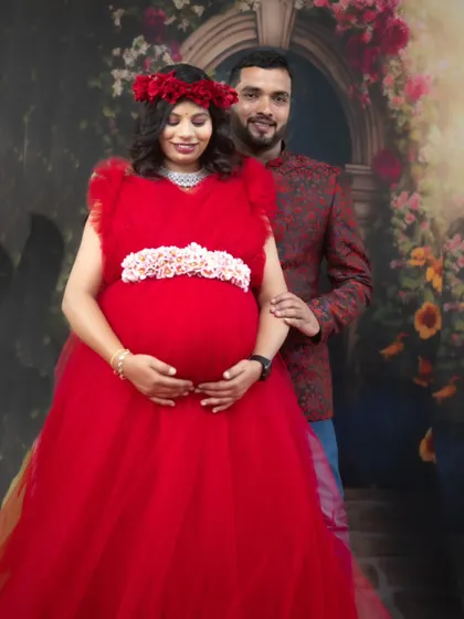 This couple looks picture-perfect for their maternity shoot, with her in a red ball gown and him in a matching patterned blazer.