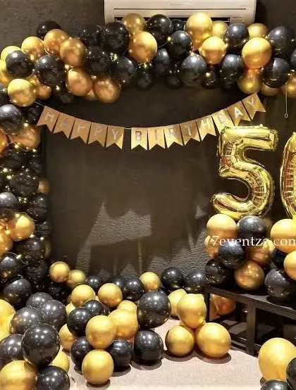 A black and gold balloon arch with large foil numbers for a 50th birthday celebration.