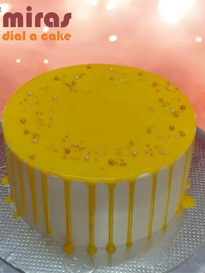 A simple white cake with a vibrant yellow drip. This design shows how a pop of color can turn a classic drip cake into a bright and cheerful centerpiece.