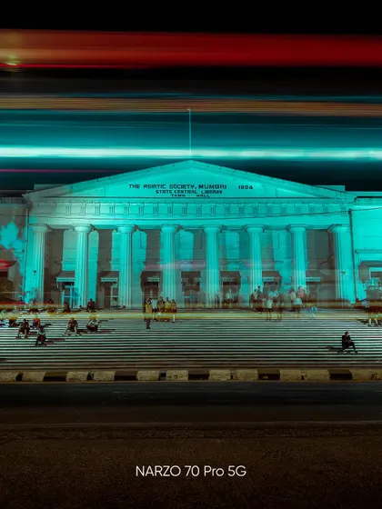 A long exposure shot of the Asiatic Society of Mumbai, with light trails from traffic creating a dynamic, energetic foreground.