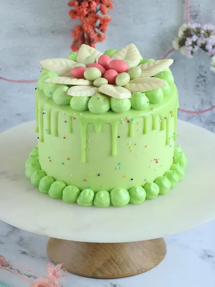 A lovely light green Easter drip cake with delicate white chocolate leaf decorations.